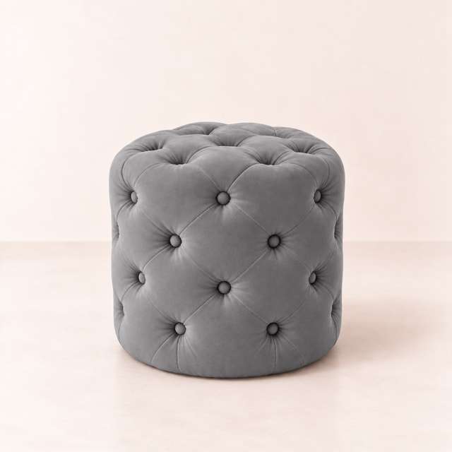 Pouf capitonné en velours gris, sur fond rose pâle